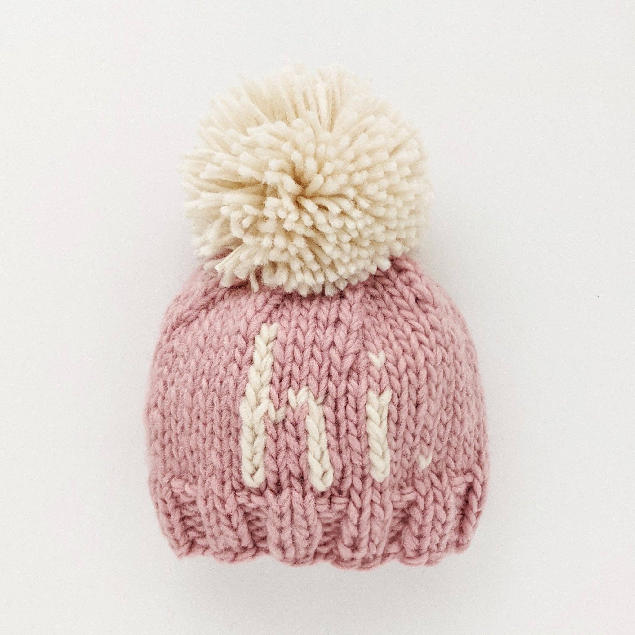 Add a playful pop of color to your little one's wardrobe with our Why Hi There Blush Beanie! Crafted with love and a cute pom on top, this hand knit beanie is the perfect gift for expecting parents or a sweet addition to your own baby's collection. Available in size 0-6 months. James 1:17
